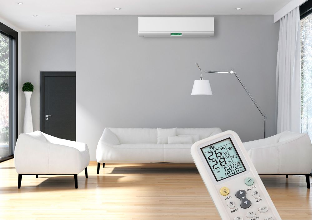 Klimatechnik im Wohnzimmer: Wand-Klimaanlage über dem Sofa und Fernbedienung zur Steuerung von Temperatur und Raumklima.