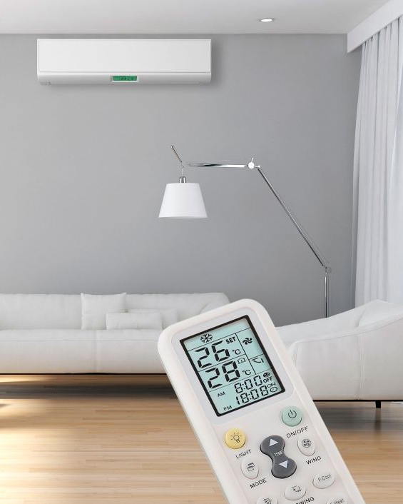 Klimatechnik im Wohnzimmer: Wand-Klimaanlage über dem Sofa und Fernbedienung zur Steuerung von Temperatur und Raumklima.